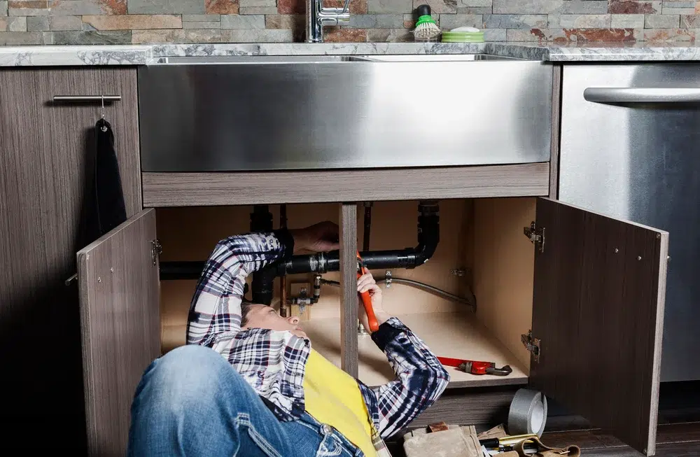 Technician working on kitchen sink plumbing