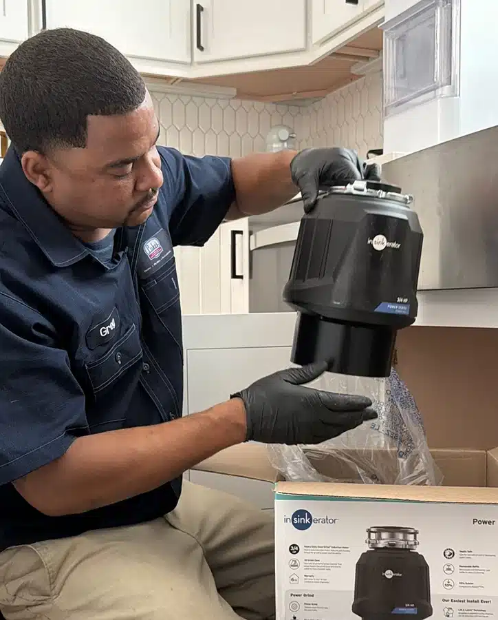 Greg from Luke's Plumbing unboxing a new InSinkErator garbage disposal for a kitchen installation in Houston