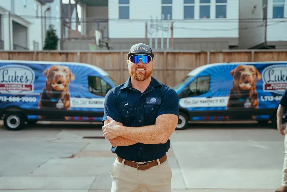 Luke's Plumbing & Air Conditioning technician in front of service vans