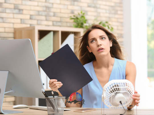 woman fanning herself, trying to cool down because AC is broken